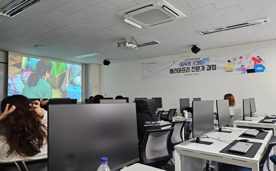 A classroom with a film playing on a projector screen during a barrier-free training course.