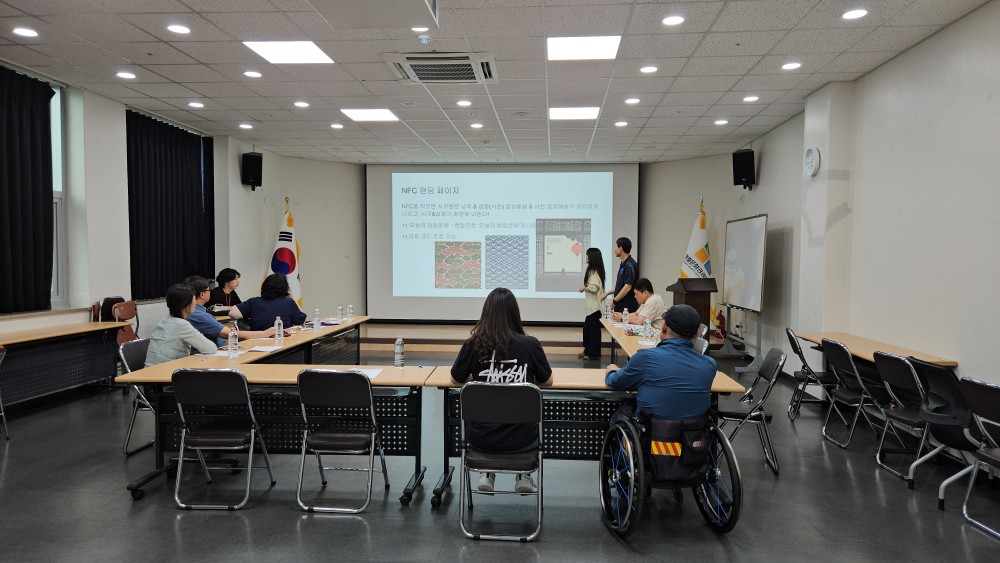 A presentation in a meeting room; attendees include a wheelchair user.